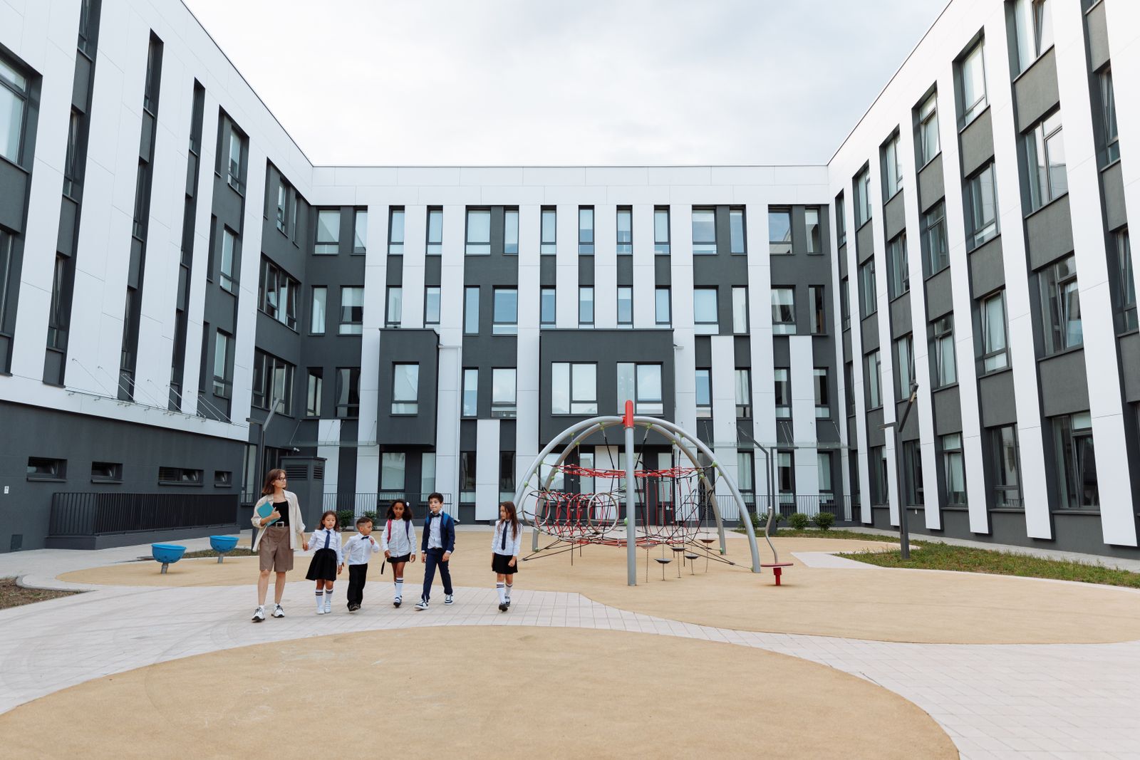 Students and a teacher walking together through the Green Valley school courtyard.