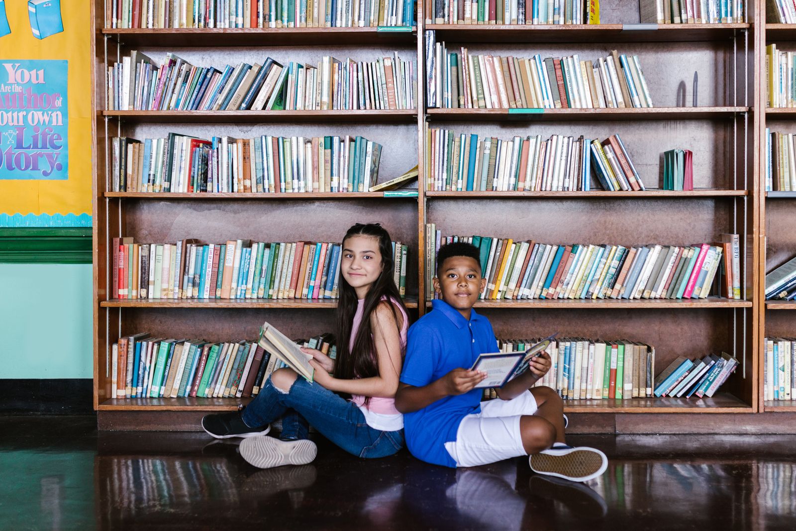Children reading together at a library table surrounded by books.