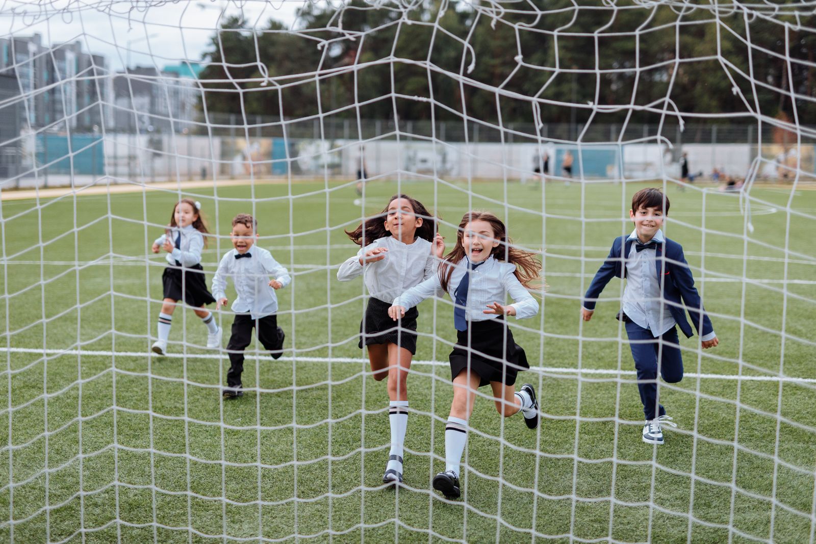 Children joyfully running on a school sports ground.