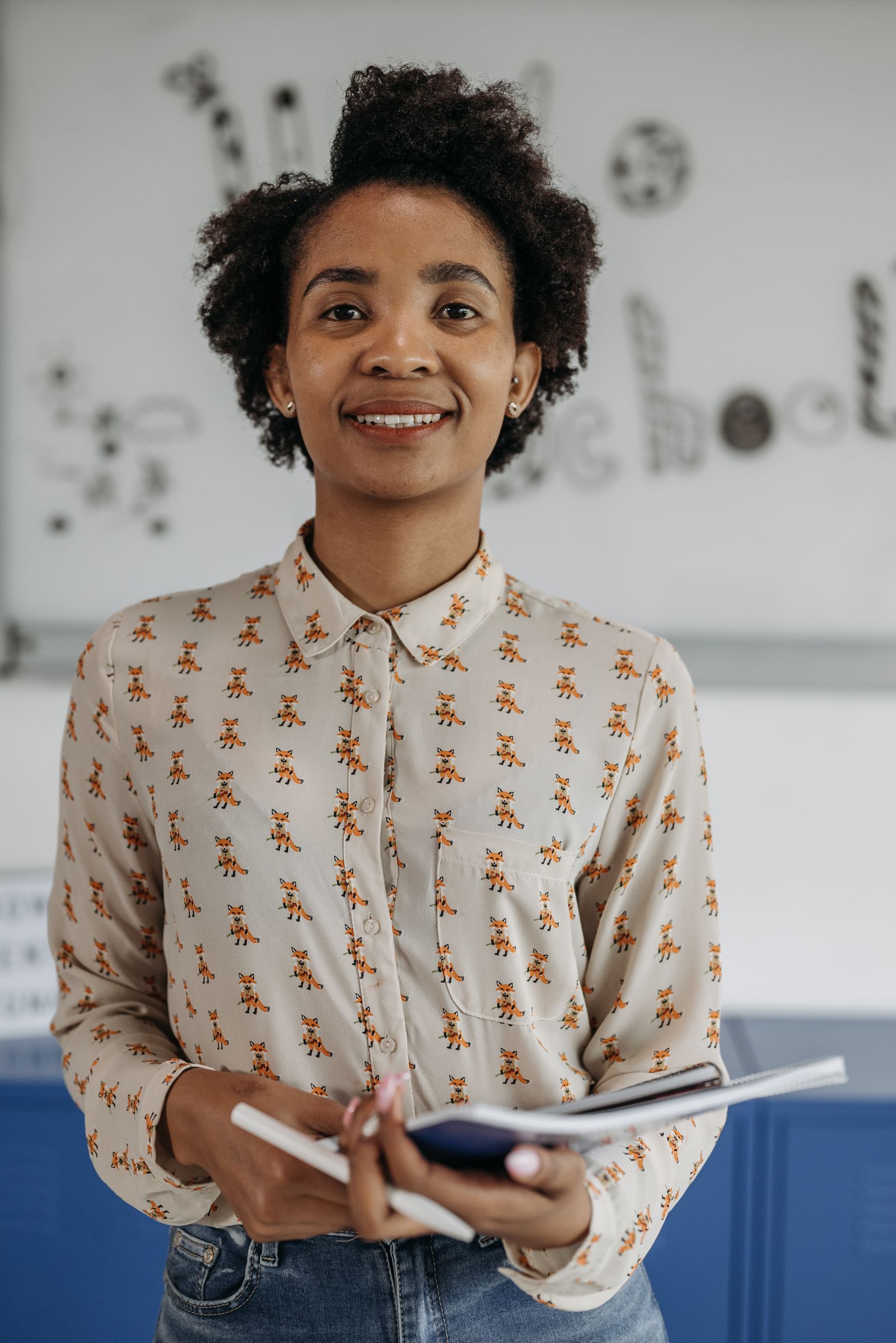 Portrait of a smiling teacher seated in a classroom.
